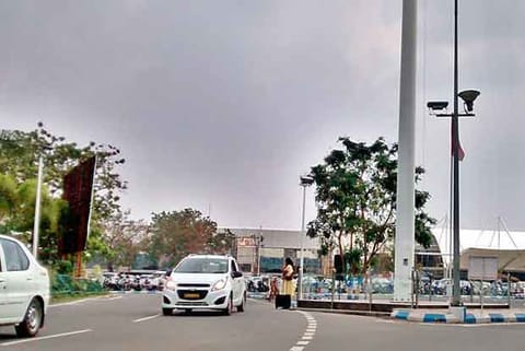 woman passenger waits with her luggage to board a cab near the entrance of the Coimbatore airport