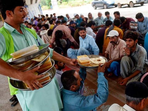 People eat food provided by a charity at a roadside in Karachi. Over-reliance on consumptive philanthropy hinders the country’s ability to address entrenched development issues such as poverty and inadequate education.