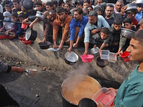 Palestinians hold containers to collect free food handouts from a volunteer hospice in Rafah, southern Gaza.