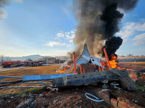 Fire and smoke rise from the tail section of a Jeju Air Boeing 737-800 series aircraft after the plane crashed and burst into flames at Muan International Airport in South Jeolla Province, southwest of Seoul on December 29, 2024.