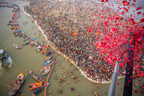 A helicopter showers flowers on devotees gather to take a dip at Triveni Sangam on the occasion of ‘Paush Purnima’ during the Maha Kumbh 2025, in Prayagraj on Monday.