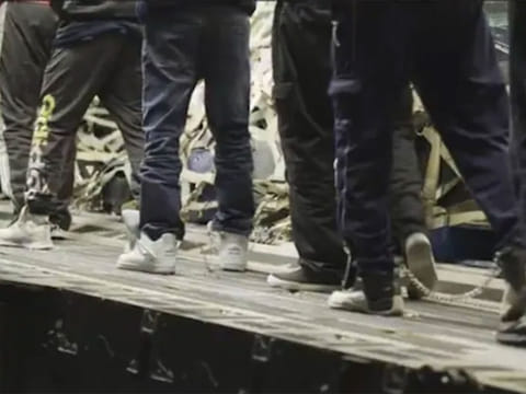 Set to dramatic music, the video showed migrants being marched aboard the C-17 transport plane, shackled at the legs, shuffling like hardened criminals.