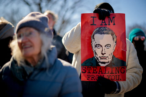 A sign depicting Tesla and SpaceX CEO Elon Musk is visible as protesters rally against the Trump administration during "Not My President's Day" protests at the Capitol Reflecting Pool on February 17, 2025 in Washington, DC.