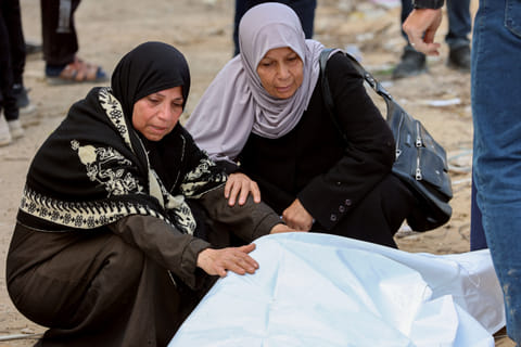 Women mourn over a body after Palestinian civil defence workers uncovered corpses buried in the grounds of Al Shifa hospital in Gaza City, on March 13, 2025.