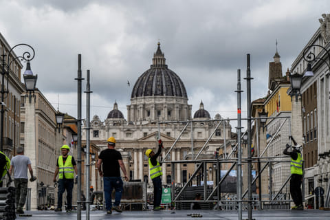 Workers build a tribune with the St Peter's Basilica of the Vatican in the background, on Via della Conciliazione street in Rome on April 25, 2025.