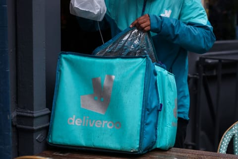 A Deliveroo courier collects an order from a restaurant in Soho, London