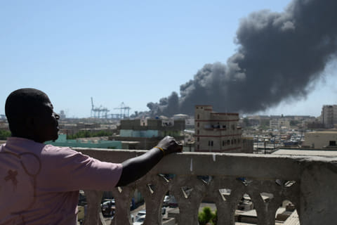 A man watches as smoke billows after a drone strike in Sudan on May 6, 2025.