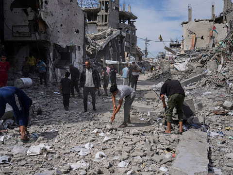 Palestinians clean the rubble along a road beside a clinic destroyed by Israeli airstrikes in Jabalia, in the northern Gaza Strip, on Thursday, May 15, 2025.