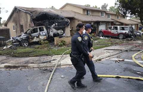 Police officers search the site where a small plane crashed on a San Diego, California, residential street on May 22, 2025