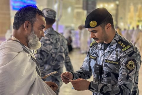 As part of a campaign to expose undocumented pilgrims, a Saudi security man checks a pilgrim’s permit at the entrance to the Grand Mosque in Mecca.