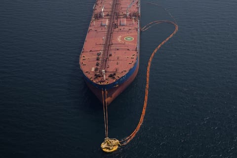 Pipes feed crude oil to a tanker.