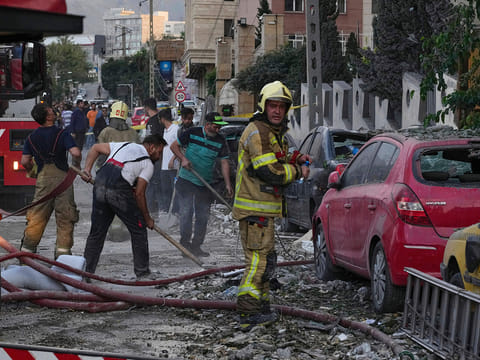 Firefighters and people clean up the scene of an explosion in a residence compound after Israel attacked Iran's capital Tehran, Friday, June 13, 2025.