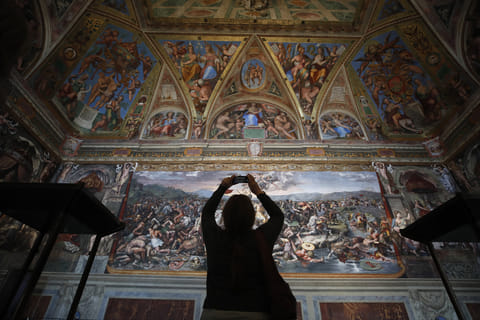 A visitor admires a Raphael Room inside the Vatican Museums at the Vatican, on May 3, 2021.