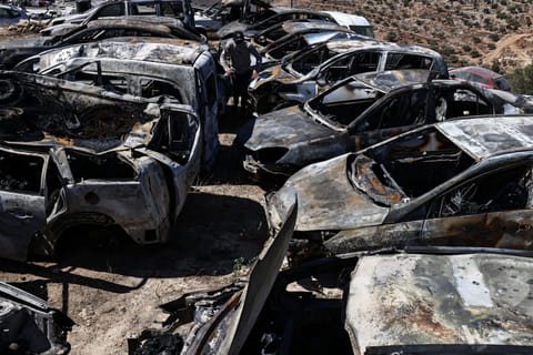 A Palestinian man walks amid destroyed cars that were set alight during a reported late-night attack by Israeli settlers on the village of Burqa, east of Ramallah in the Israeli-occupied West Bank on July 15, 2025.