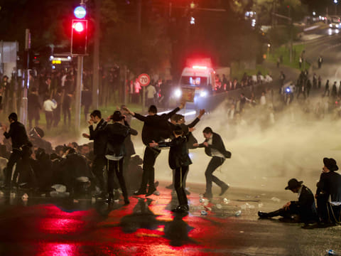 Israeli police uses a water canon to disperse ultra-Orthodox Jewish demonstrators as they protest their conscription in Israel's military and the arrest of religious school students who avoided draft orders, during a rally in Jerusalem on August 7, 2025.