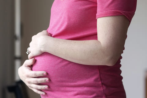 A pregnant woman stands for a portrait in Dallas, May 18, 2023. Photo used for illustrative purposes.
