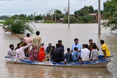 Flood-affected people evacuate on a boat amid rising water levels after heavy rainfall in the Haqu Wala village of Pakistan's Kasur district on August 24, 2025.