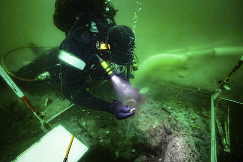 A diver excavates an 8,500-year-old Stone Age coastal settlement, submerged by sea level rise in the Bay of Aarhus, Denmark.