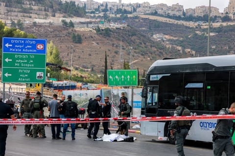 Israeli security forces gather by a body next to a bus at the Ramot road junction in Israeli-annexed east Jerusalem on September 8, 2025.