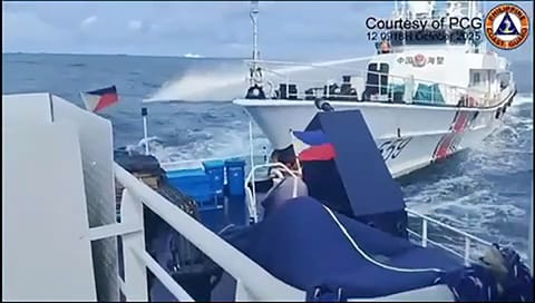 This frame grab from handout video footage taken and released on October 12, 2025 by the Philippine Coast Guard shows a China Coast Guard ship (R) deploying water cannon as seen from a Philippine Bureau of Fisheries vessel during an incident near Thitu island in disputed waters of the South China Sea.