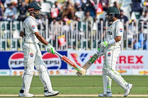 Pakistan's captain Shan Masood (L) and his teammate Babar Azam bump their bats during the first day of the second Test cricket match against South Africa at the Rawalpindi Cricket Stadium in Rawalpindi on October 20, 2025.