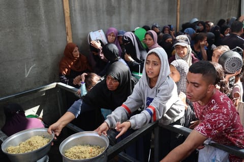 Palestinian children gather to receive food portions from a charity kitchen in the Nuseirat refugee camp, located in the central Gaza Strip, on October 21, 2025, a week after a ceasefire came into effect.