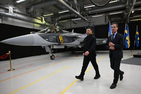 Swedish Prime Minister Ulf Kristersson (R) and Ukrainian President Volodymyr Zelensky walk past a Gripen fighter jet after they delivered a joint press conference in Linkoping, Sweden, on October 22, 2025.