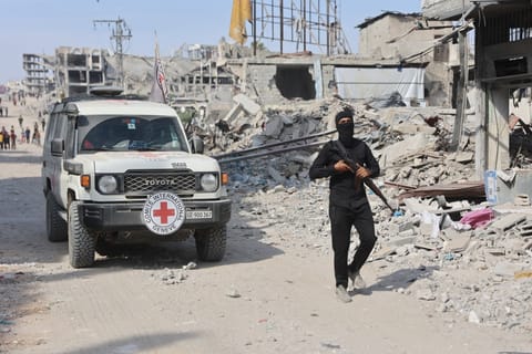An armed Palestinian Hamas militant stand not far from an International Red Cross (ICRC) vehicle, as a search for the bodies of killed Israeli hostages takes place, in Gaza City on November 2, 2025.