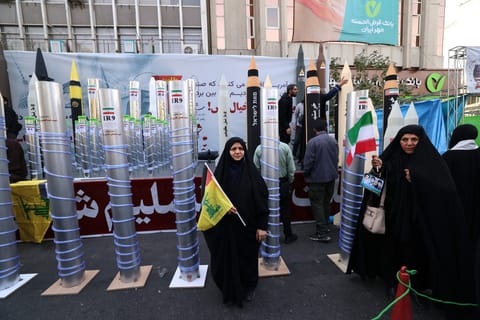 Women stand next to model missiles and a nuclear enrichment centrifuge during a rally outside the former US embassy in Tehran in a November 4, 2025, file photo..