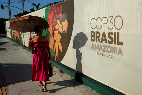 A woman walks past a sign for the COP30 UN Climate Summit, in Belem, Para state, Brazil, Tuesday, November 4, 2025.