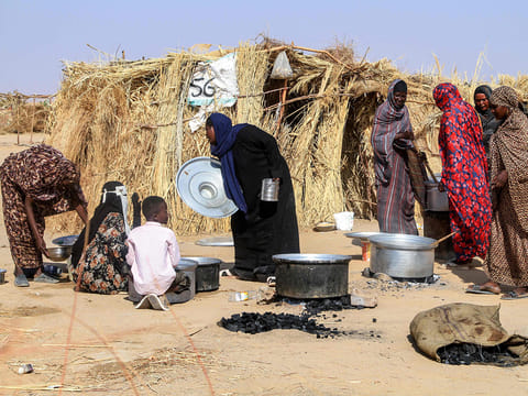 Sudanese people who fled Al-Fashir prepare a meal at a camp for displaced Sudanese people in the northern town of Al-Dabba on November 13, 2025.