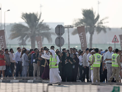 Police officers give instructions to people queueing for the 2025 Dubai Airshow at Al Maktoum International Airport after an Indian fighter jet crashed during a flying display in Dubai on November 21, 2025.