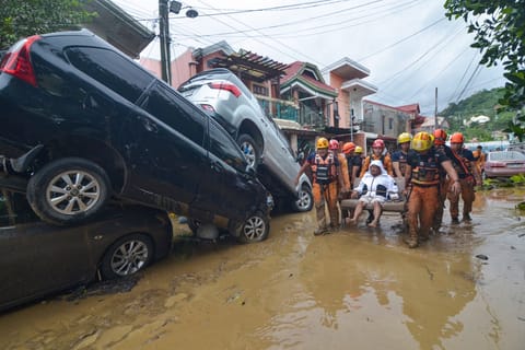 Flood aftermath: Rescuers carry a resident past cars washed away by floods at the height of Typhoon Kalmaegi (Tino) at a subdivision of Cebu City in the central Philippines on November 4, 2025.