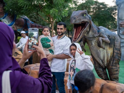 Visitors strike a pose with a lifelike dinosaur at Dubai Garden Glow’s Season 11 reopening.