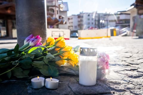 Flowers and candles laid on the ground near the bar Le Constellation following a fire that ripped through the venue in Crans-Montana, during New Year's Eve celebrations.