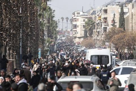 Residents carry their belongings as they flee Aleppo's Ashrafieh Kurdish neighbourhood on January 7, 2026.
