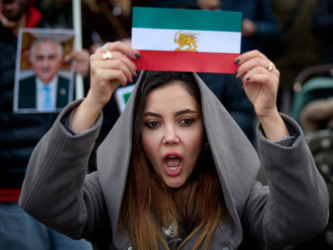 A protester shows an Iran's pre-1979 Islamic Revolution flag during a demonstration to support mass rallies denouncing the Islamic republic in Iran in Paris on January 11, 2026.