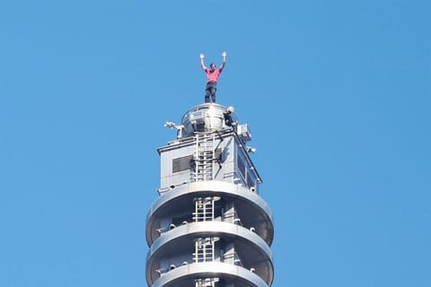 US rock climber Alex Honnold raises his arms from the top of the Taipei 101 building after he successfully free soloed the landmark skyscraper without ropes or safety gear in Taipei on January 25, 2026.