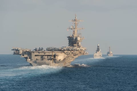 The USS Abraham Lincoln aircraft carrier (L) transits the Strait of Hormuz on November 19, 2019.
