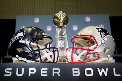The Vince Lombardi Trophy is framed by the Seattle Seahawks and New England Patriots helmets during Super Bowl LX Opening Night at San Jose McEnery Convention Center