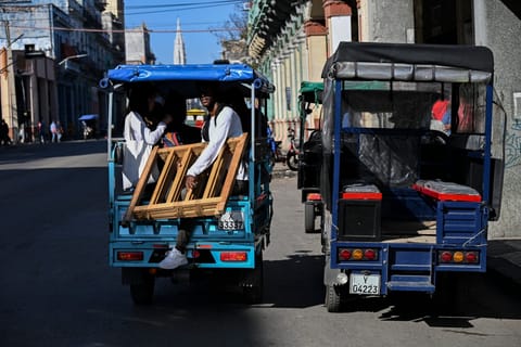 People ride an electric tricycle as another is parked on a street in Havana on February 13, 2026.