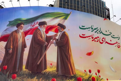 A banner is displayed at Valiasr Square in central Tehran on March 10, 2026, depicting Iran's late supreme leader Ayatollah Ruhollah Khomeini watching as his successor the late Ayatollah Ali Khamenei hands over a national flag to his son and new supreme leader Mojtaba Khamenei.