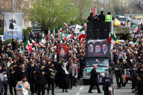 A hearse decorated with pictures of Iranian spiritual leader Ayatollah Ruhollah Khomeini, Iran's slain supreme leader Ayatollah Ali Khamenei and Iran's new Supreme Leader Ayatollah Mojtaba Khamenei drives past Iranians attending the funeral ceremony of Iran's Revolutionary Guards spokesperson Ali Mohammad Naini, who was killed in US-Israeli strikes, in Tehran on March 21, 2026.