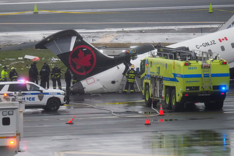 Firefighters and investigators examine the site, Monday, March 23, 2026, where an Air Canada jet came to rest after colliding with a Port Authority firetruck at LaGuardia Airport, after landing Sunday night in New York.