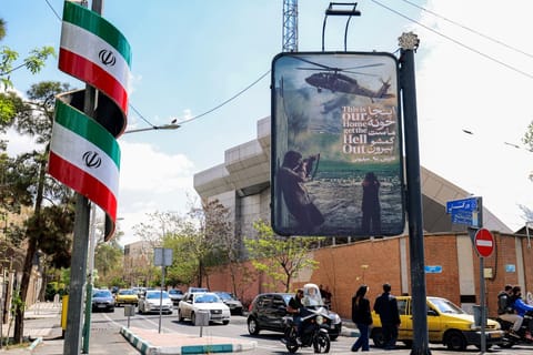 An anti-US banner depicting a helicopter being fired upon is displayed along a street in Tehran on April 6, 2026.