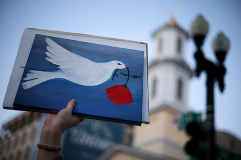 An Anti-war demonstrator holds up a sign with a symbol of peace as they gather near the White House to protest the war in Iran on April 7, 2026 in Washington, DC.
