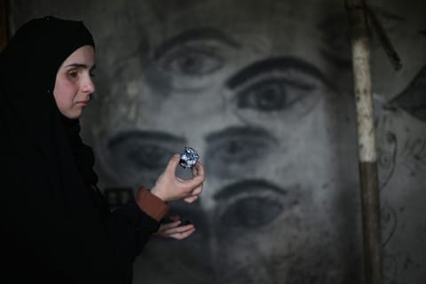 Areej al-Saafin, who lost her eye as a result of an Israeli military strike, holds a piece of wood charcoal as she prepares to draw on the wall of her home in the Bureij Palestinian refugee camp in the central Gaza Strip.