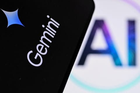 A photo taken on May 7, 2026 shows the letters AI for Artificial Intelligence on a laptop screen (R) next to the logo of the Google's Gemini chatbot application on a smartphone screen in Frankfurt am Main, western Germany.