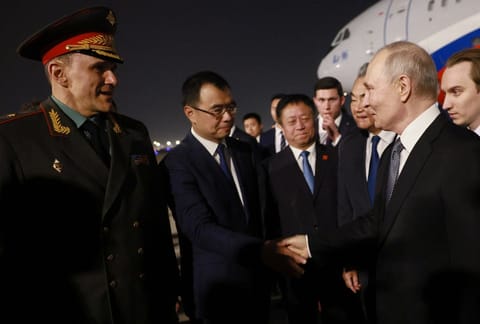 In this pool photograph distributed by the Russian state agency Sputnik, Russia's President Vladimir Putin is welcomed by Chinese Foreign Minister Wang Yi and other officials upon his arrival at Beijing Capital Airport in Beijing late on May 19, 2026.