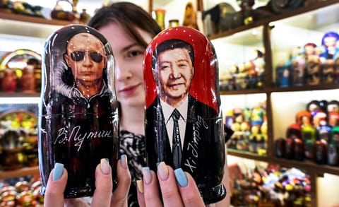A vendor offers traditional Russian wooden nesting dolls, Matryoshka dolls, depicting Russian President Vladimir Putin and Chinese President Xi Jinping at a gift shop in downtown Moscow on May 19, 2026, as the Russian leader in on a visit to Beijing on May 19-20.